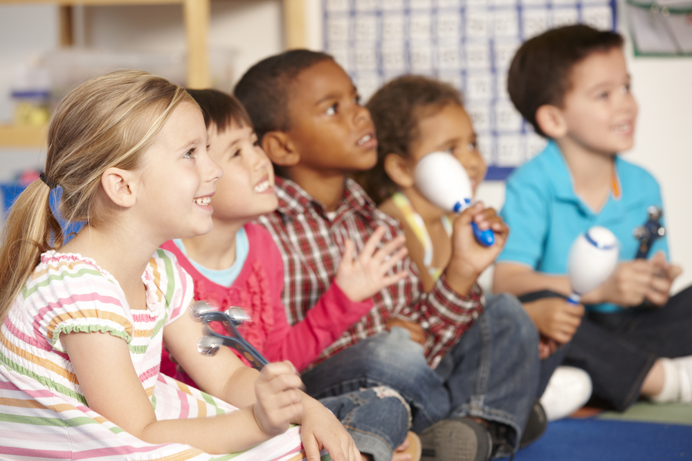 Group,Of,Elementary,Age,Schoolchildren,In,Music,Class,With,Instruments A group of smiling young children plays handheld percussion instruments during an early childhood music class.