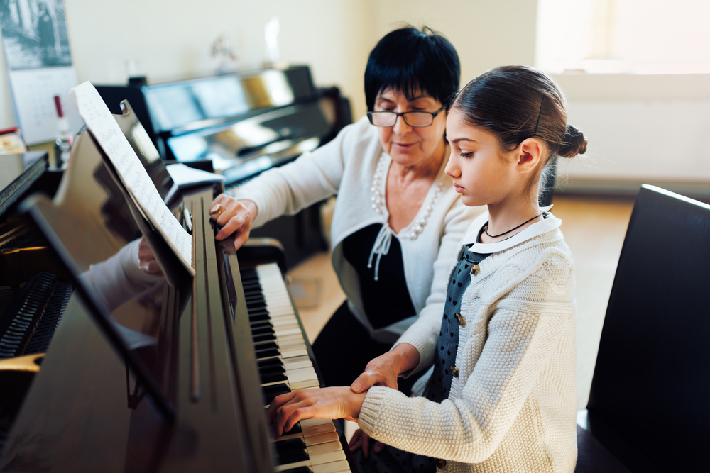 A,Music,Teacher,With,The,Pupil,At,The,Lesson,Piano A young piano student receives focused instruction from her teacher during a one-on-one lesson.