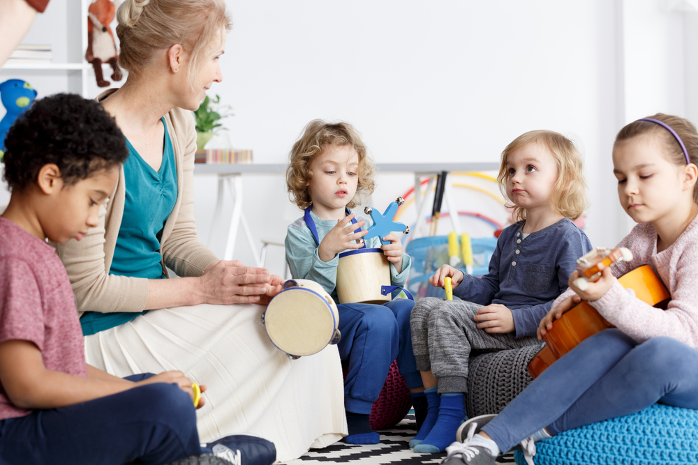 Four,Preschoolers,Having,Fun,In,Kindergarten,Playing,The,Instruments A group of young children explores rhythm and sound with hand instruments during an early childhood music class.