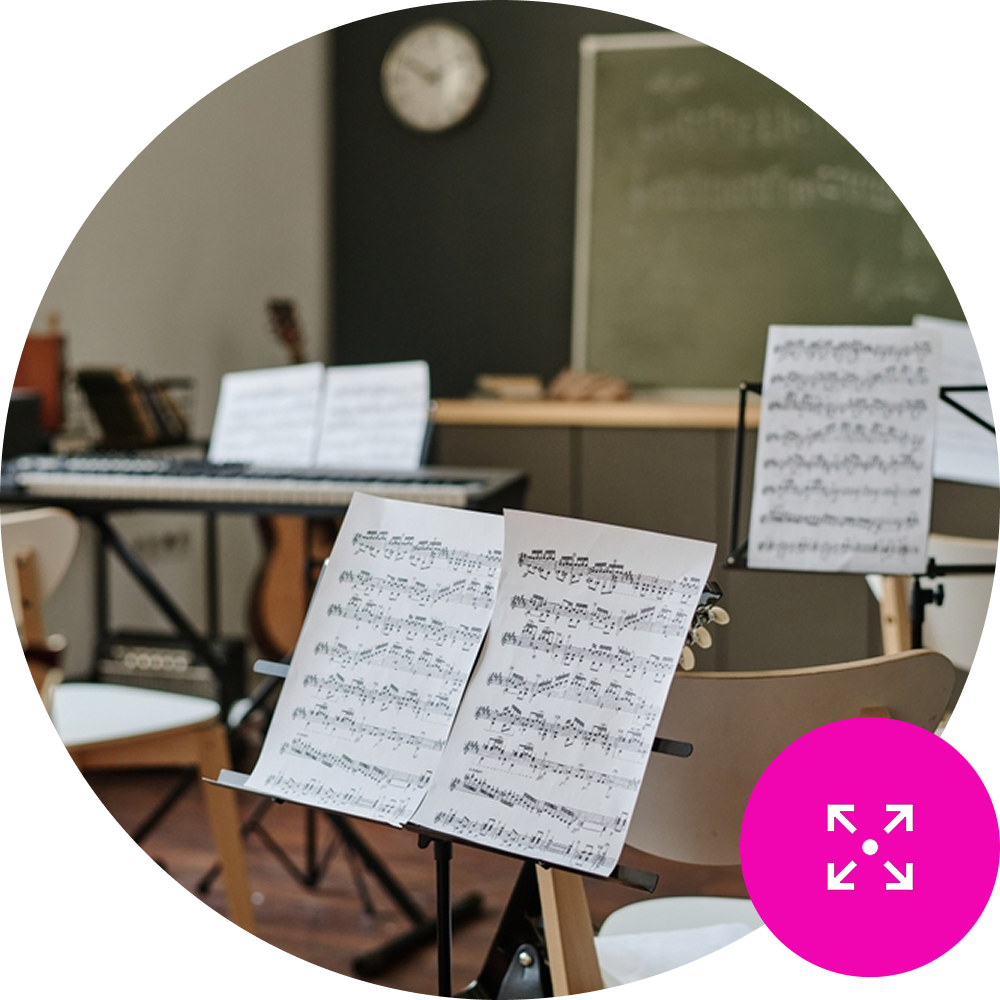 Resource Management Featured Image – Detail Sheet music on a stand in an empty music classroom - Resource Management Icon in the bottom right on brand pink background